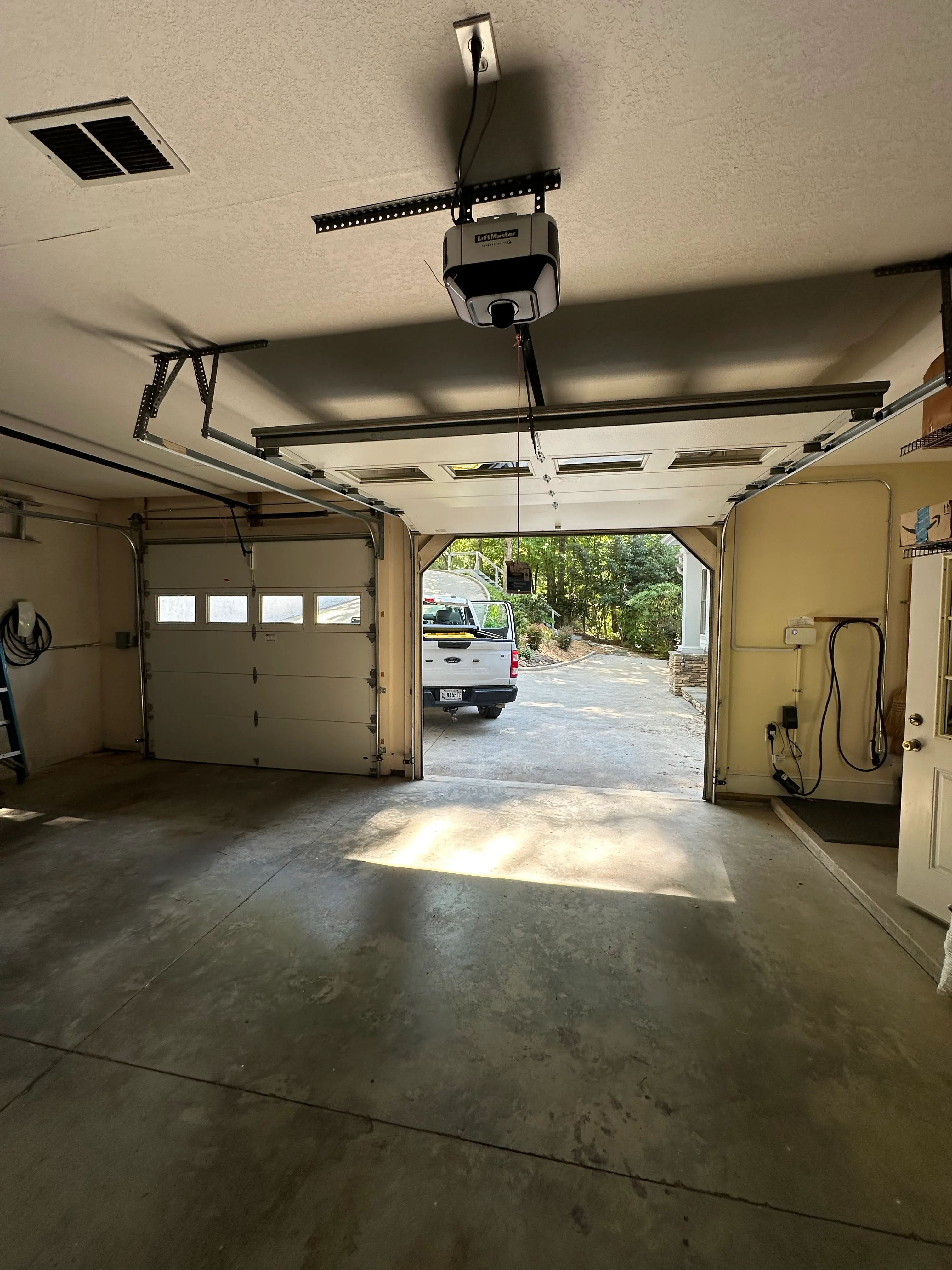 Two-car garage with wall-mounted charging equipment and metal conduit on the right wall